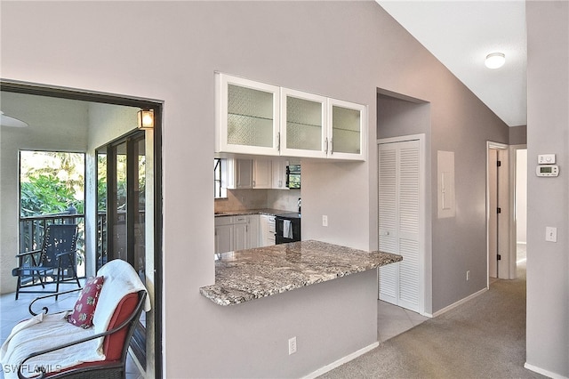 kitchen with light carpet, vaulted ceiling, electric range, light stone countertops, and white cabinetry