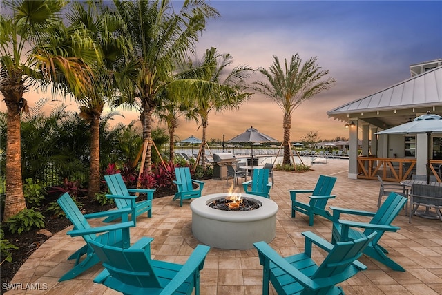 patio terrace at dusk with a fire pit and area for grilling