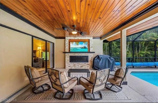 view of patio featuring ceiling fan, a large fireplace, glass enclosure, and a grill