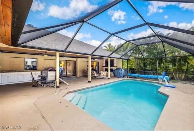 view of swimming pool with ceiling fan, a lanai, and a patio