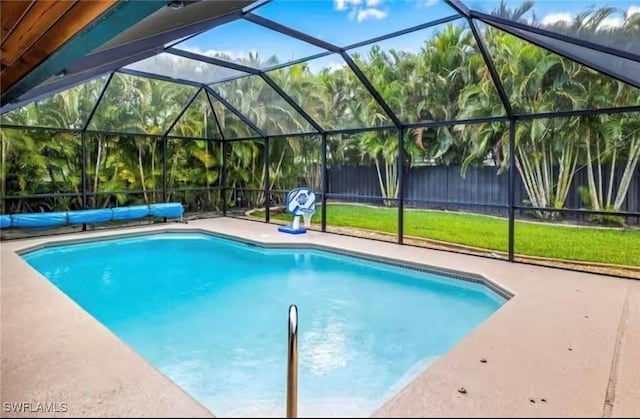 view of swimming pool with a lanai, a lawn, and a patio