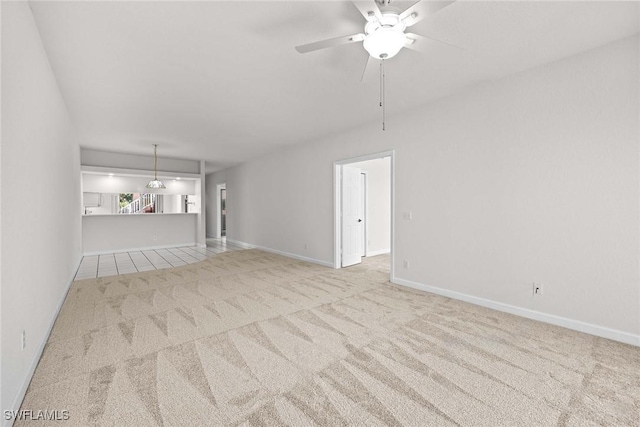 unfurnished living room featuring carpet, baseboards, and ceiling fan