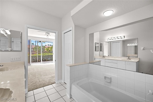 bathroom featuring a textured ceiling, vanity, a bath, and tile patterned floors