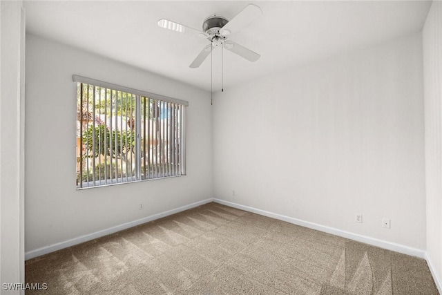 carpeted spare room with ceiling fan and baseboards