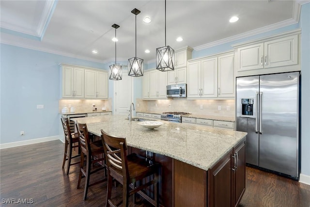 kitchen featuring light stone counters, a center island with sink, decorative light fixtures, and appliances with stainless steel finishes