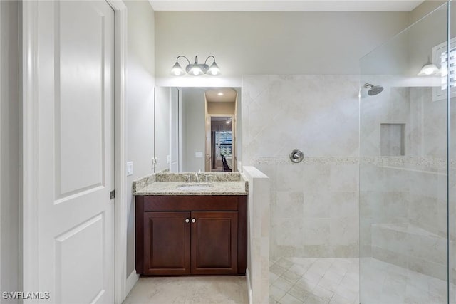 bathroom with a tile shower and vanity