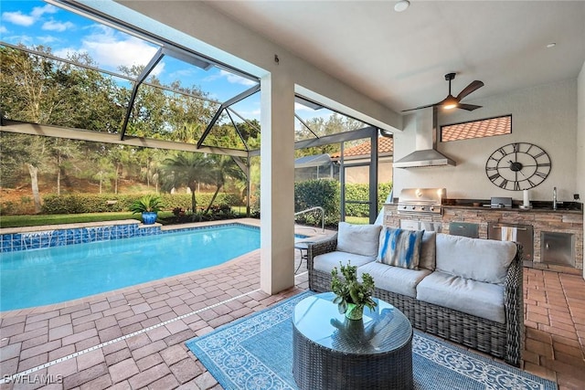 view of pool with glass enclosure, area for grilling, a patio area, and exterior kitchen