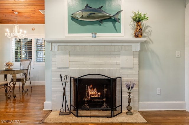 room details featuring an inviting chandelier, a brick fireplace, and hardwood / wood-style flooring