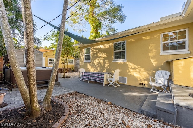 back of property with a patio area, a hot tub, and stucco siding