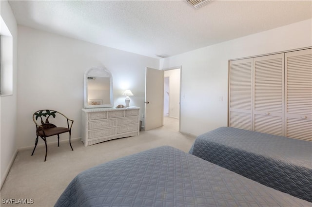 bedroom featuring light colored carpet, a textured ceiling, and a closet