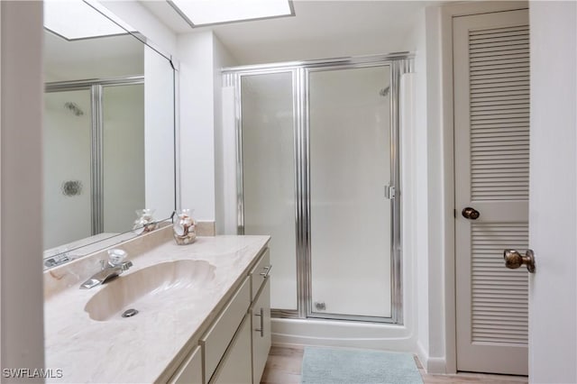 bathroom featuring hardwood / wood-style flooring, vanity, and walk in shower