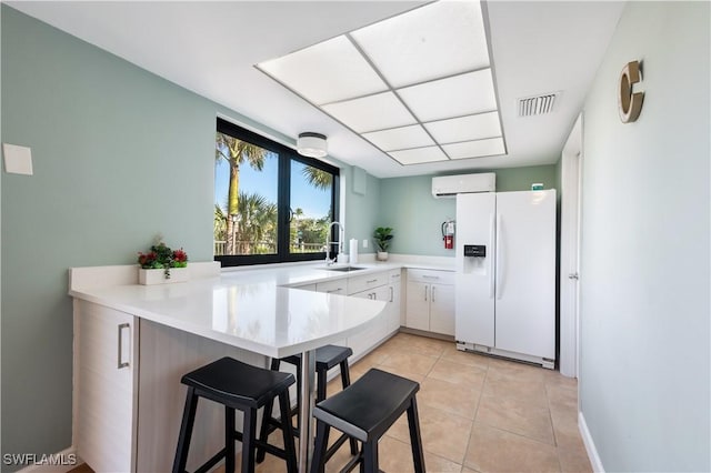 kitchen featuring kitchen peninsula, a wall mounted air conditioner, sink, white refrigerator with ice dispenser, and white cabinetry