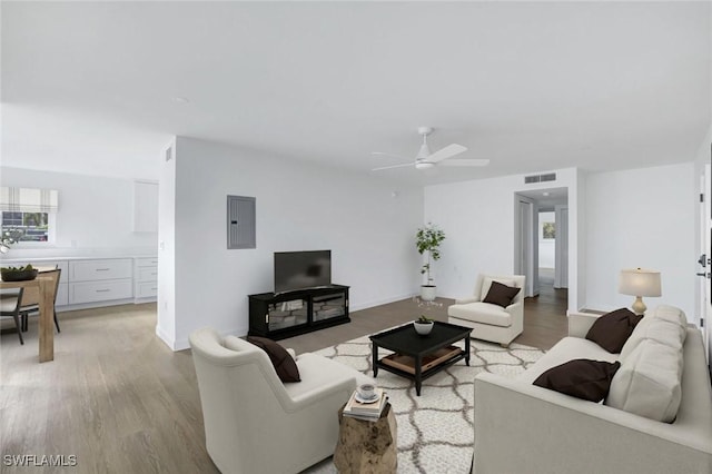 living room with electric panel, light hardwood / wood-style flooring, and ceiling fan