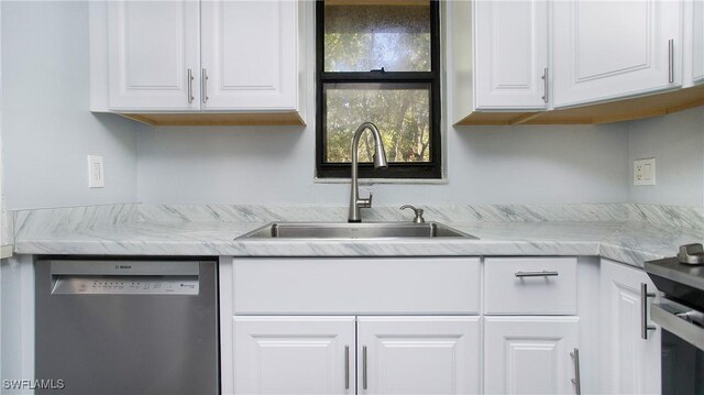 kitchen featuring light stone counters, white cabinetry, stainless steel dishwasher, and sink