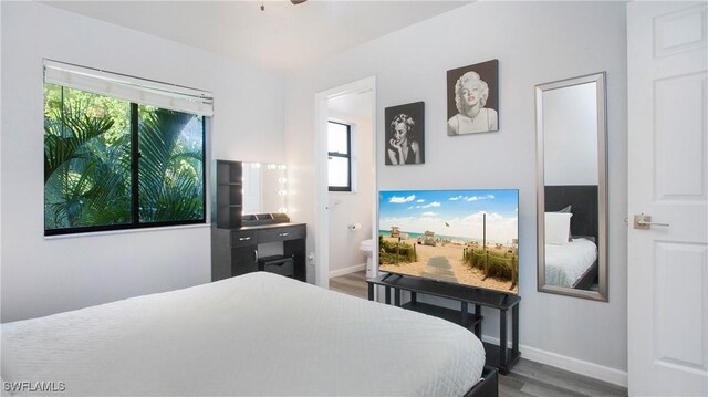 bedroom featuring connected bathroom and hardwood / wood-style flooring