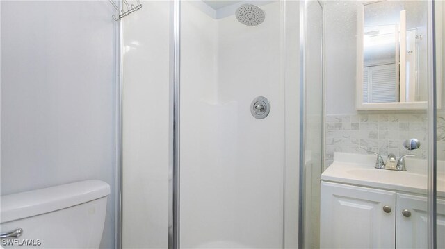 bathroom featuring backsplash, vanity, an enclosed shower, and toilet