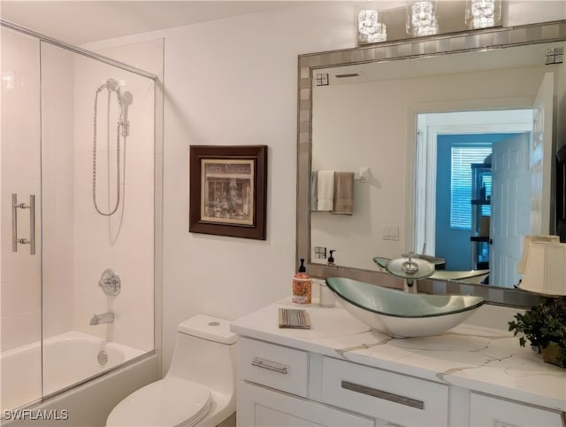 bathroom featuring enclosed tub / shower combo, toilet, and vanity