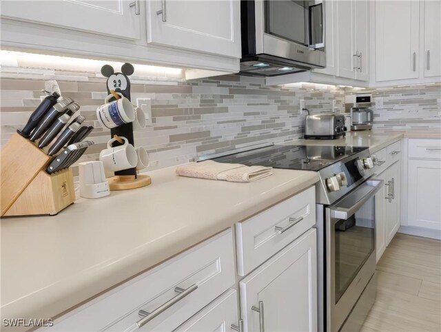 kitchen featuring tasteful backsplash, appliances with stainless steel finishes, white cabinets, and light countertops