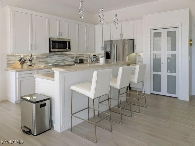 kitchen with light countertops, white cabinets, backsplash, and appliances with stainless steel finishes