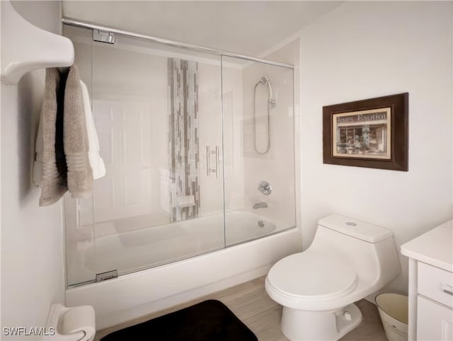 full bathroom featuring vanity, toilet, wood finished floors, and bath / shower combo with glass door