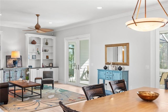 dining area with french doors, light wood-type flooring, ceiling fan, and crown molding