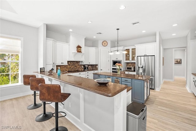 kitchen featuring white cabinets, a center island, stainless steel fridge, and backsplash