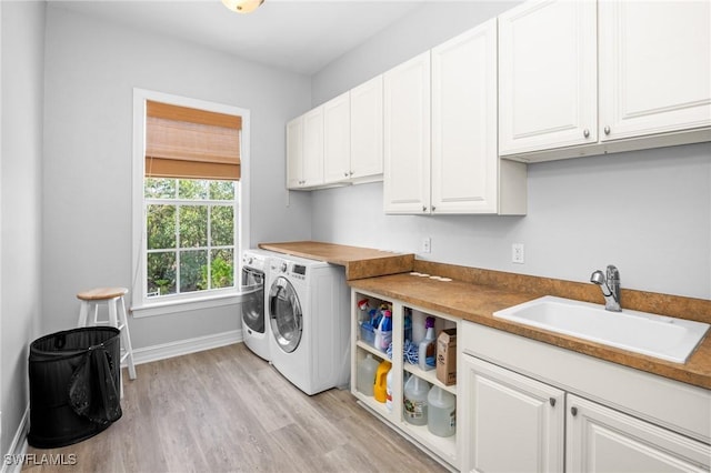 laundry room with cabinets, independent washer and dryer, light hardwood / wood-style floors, and sink