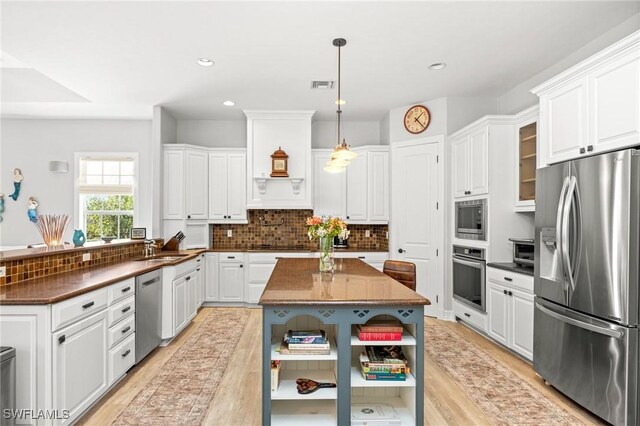 kitchen with white cabinets, stainless steel appliances, and light wood-type flooring