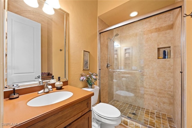 bathroom featuring vanity, toilet, and a shower with shower door