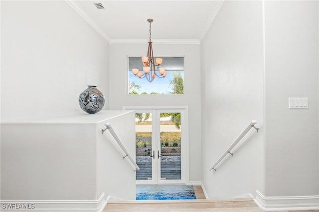 stairway with wood-type flooring, an inviting chandelier, french doors, and ornamental molding