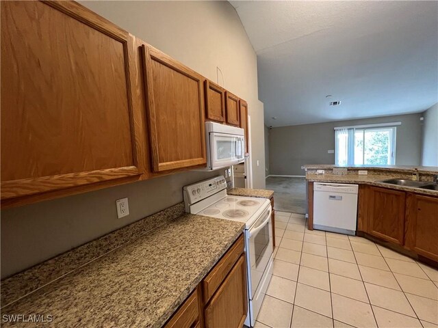 kitchen featuring light tile patterned floors, white appliances, lofted ceiling, light stone counters, and sink