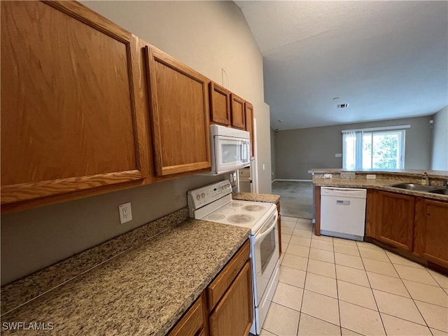 kitchen with sink, white appliances, light tile patterned floors, light stone counters, and vaulted ceiling