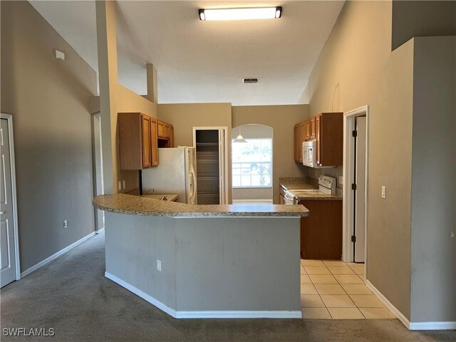 kitchen featuring vaulted ceiling, light tile patterned floors, kitchen peninsula, and white appliances