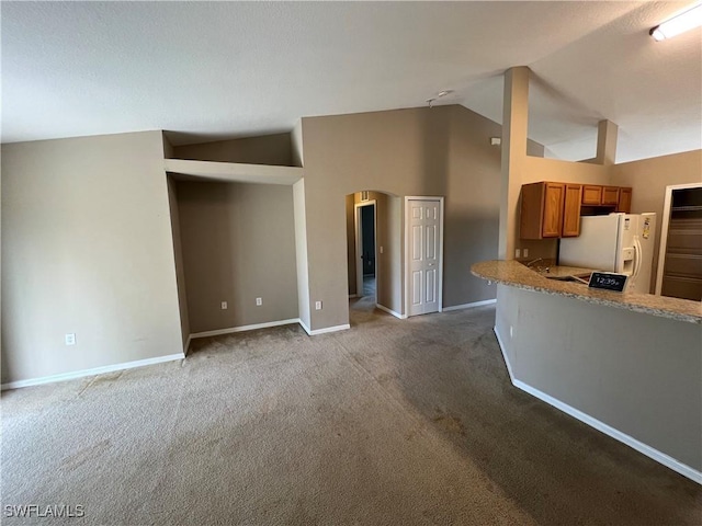 kitchen with carpet, white refrigerator with ice dispenser, kitchen peninsula, and high vaulted ceiling