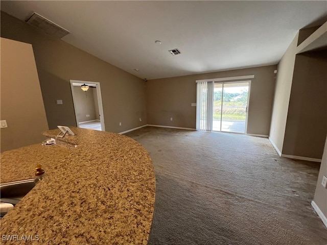 interior space with lofted ceiling, dark carpet, and ceiling fan