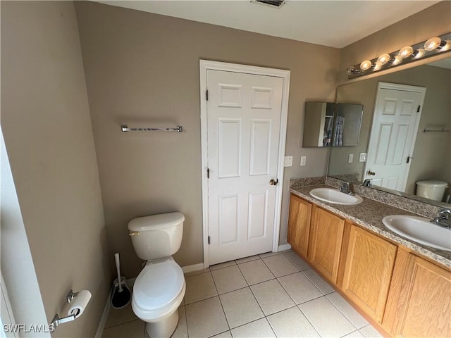 bathroom with toilet, vanity, and tile patterned floors