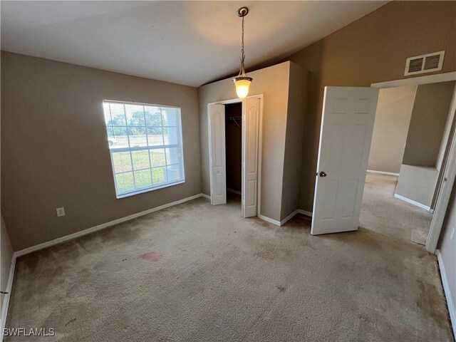 unfurnished bedroom with a closet, lofted ceiling, and light colored carpet