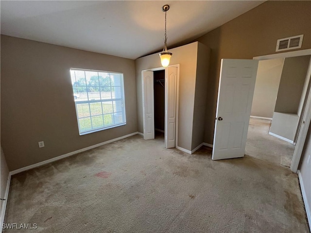 unfurnished bedroom with lofted ceiling, light colored carpet, and a closet