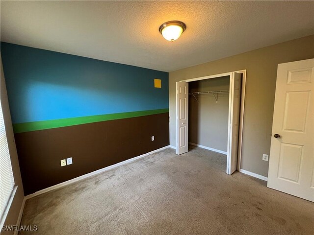 unfurnished bedroom with a textured ceiling, a closet, and light colored carpet