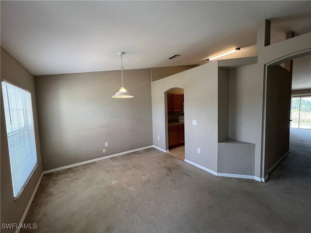 carpeted spare room featuring vaulted ceiling