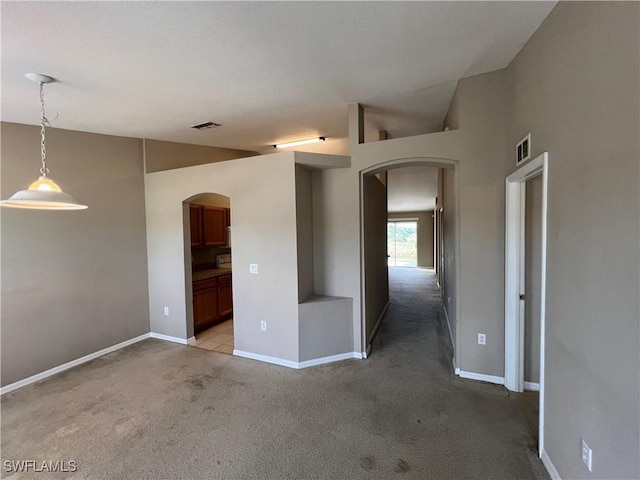 spare room featuring lofted ceiling and light colored carpet