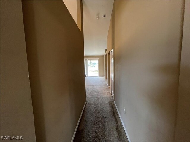 corridor featuring carpet and a towering ceiling