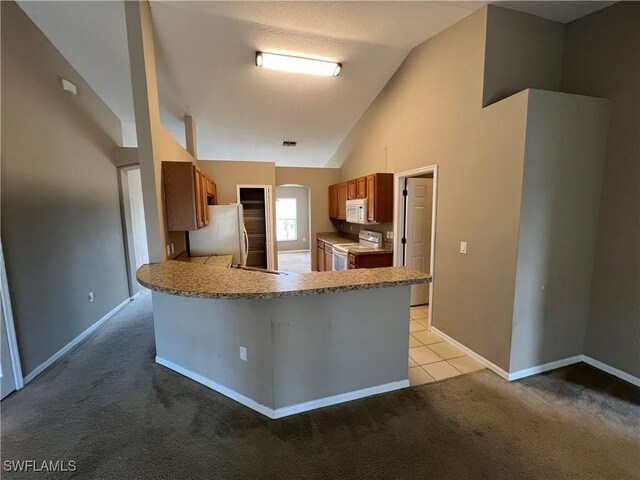 kitchen with white appliances, light carpet, kitchen peninsula, and vaulted ceiling