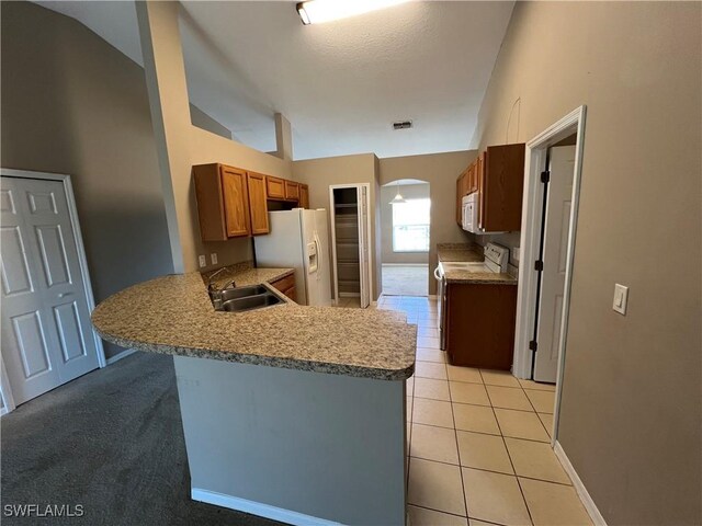 kitchen with kitchen peninsula, white appliances, light tile patterned flooring, lofted ceiling, and sink