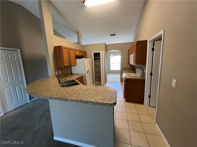 kitchen featuring light tile patterned flooring, a kitchen bar, sink, kitchen peninsula, and white appliances