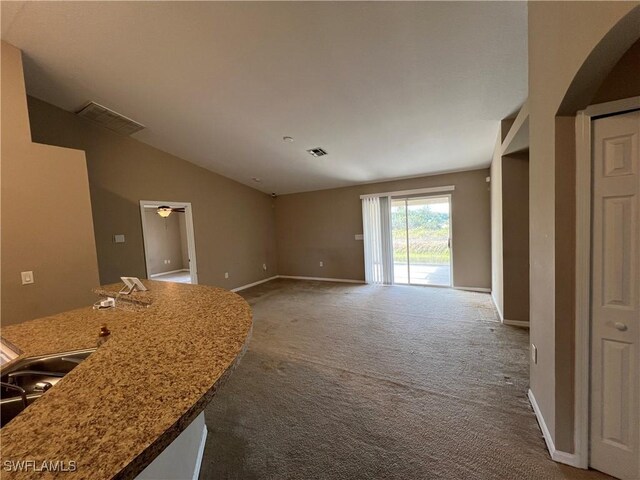 unfurnished living room featuring lofted ceiling, carpet floors, and sink