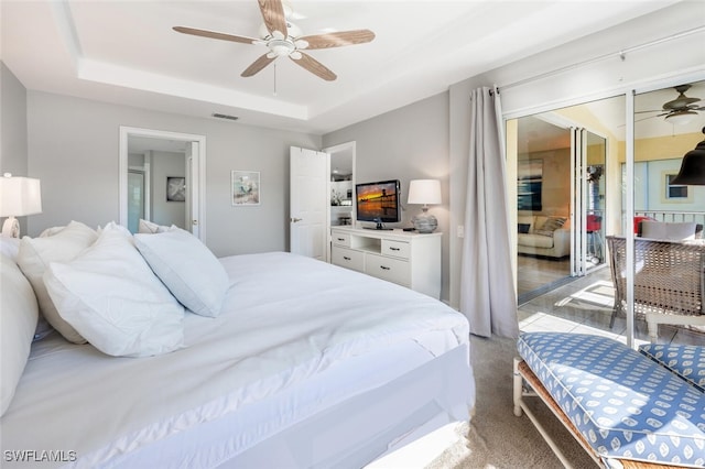 carpeted bedroom with a tray ceiling, a closet, and ceiling fan