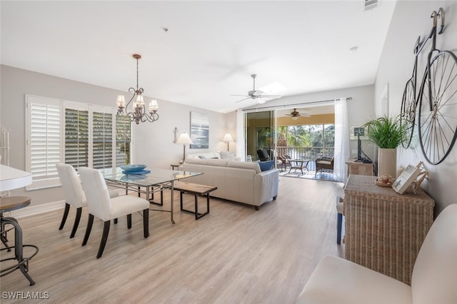 dining room featuring ceiling fan with notable chandelier, light hardwood / wood-style floors, and vaulted ceiling