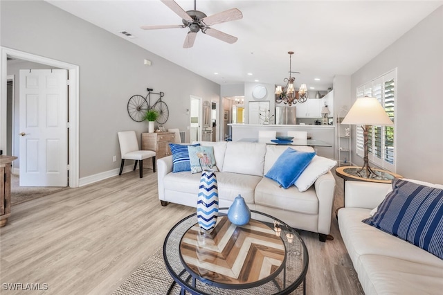 living room featuring ceiling fan with notable chandelier and light hardwood / wood-style floors