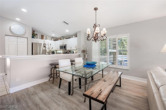 dining room with light wood-type flooring, an inviting chandelier, and lofted ceiling